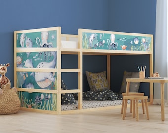 May include: A wooden bunk bed with a blue and green ocean-themed wallpaper featuring sea creatures like whales, narwhals, and an octopus. The bed has a white mattress and a blue and white patterned pillow.