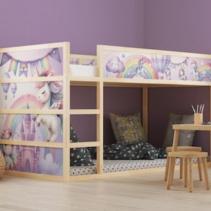Op de afbeelding: Een houten stapelbed met een grillig eenhoornthema. Het bed heeft kleurrijke illustraties van eenhoorns, regenbogen en kastelen. Het ontwerp omvat een lager slaapgedeelte en een bovenste stapelbed.