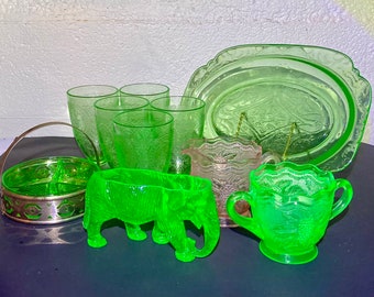 May include: A collection of vintage green Depression glass, including a serving dish, a creamer, a sugar bowl, four tumblers, a small bowl, and a green glass elephant figurine.