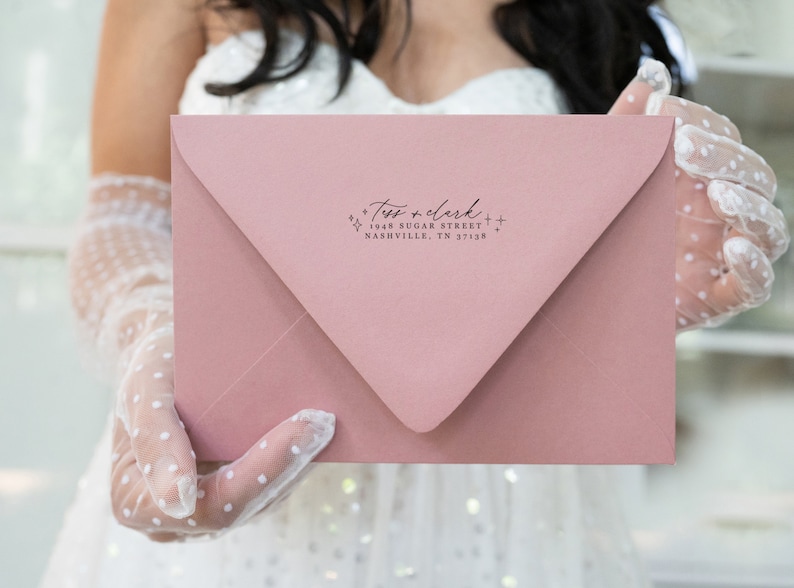 May include: A pink envelope with a return address label that reads "Tess + Clark + 1948 Sugar Street Nashville, TN 37138"