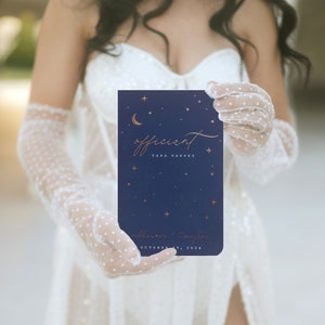 May include: A navy blue wedding invitation with gold lettering and celestial design elements, including a crescent moon and stars. The invitation reads "officient" and includes names and a date.