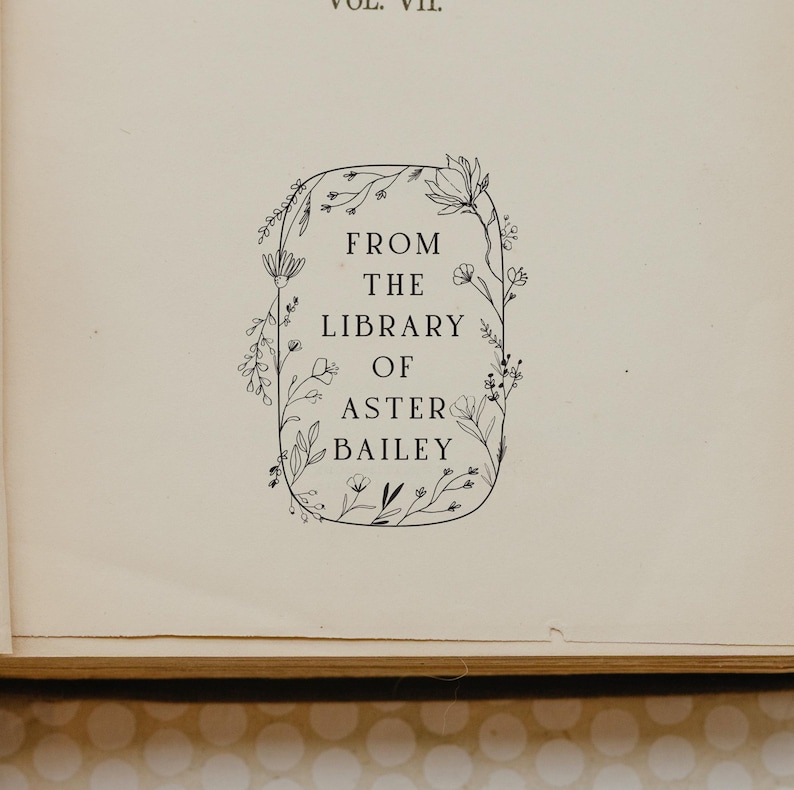 May include: A black and white illustration of a floral border with the text "From the Library of Aster Bailey" inside.