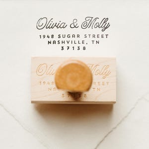 以下が含まれることがあります： 「Olivia & Molly」、「1948 Sugar Street」、「Nashville, TN」、「37138」のテキストが刻印された木製のリターンアドレススタンプ。