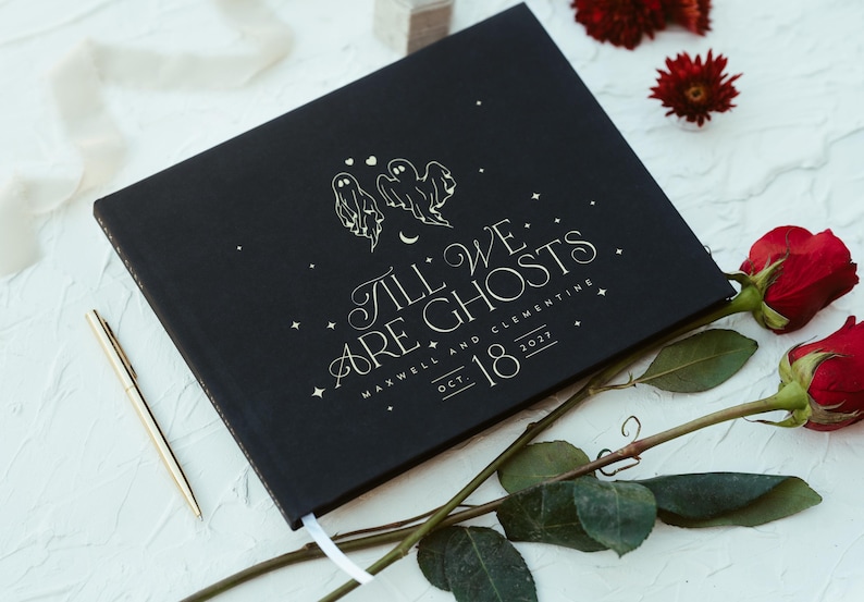 May include: Black hardcover book with the text "Till We Are Ghosts" and the date Oct. 18, 2021. The cover features illustrations of two ghosts and stars. A gold pen and red roses are also in the image.