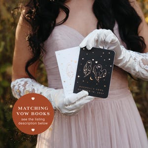 May include: Two vow books are held in white gloves. One book is black with gold ghost illustrations and the text "MAXWELL'S VOWS OCTOBER 18, 2027". The other book is white with a gold ghost illustration. The text "MATCHING VOW BOOKS see the listing description below" is in the image.