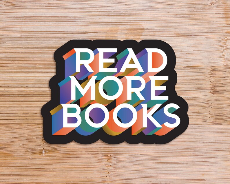 May include: A die-cut sticker featuring the text READ MORE BOOKS in a bold, three-dimensional block font. The letters are white with colorful, multi-toned sides in shades of orange, blue, green, and purple, all outlined by a thick black border.