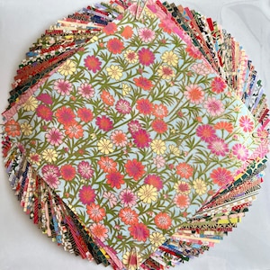 Peut inclure: Une pile de papier origami &agrave; motifs color&eacute;s, avec une seule feuille de papier bleu clair avec un motif floral sur le dessus. Le motif floral pr&eacute;sente des fleurs roses, rouges et jaunes sur un fond bleu clair.