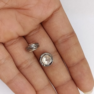 Op de afbeelding: Twee zilverkleurige ronde kralen met heldere kristallen accenten. De kralen zijn gezet in een zilverkleurig metalen frame.
