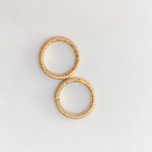 Puede incluir: Dos pendientes de aro de oro con engaste pavé de piedras transparentes.