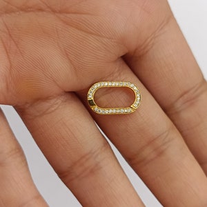 Könnte beinhalten: Ein goldener ovaler Anhänger mit einem klaren Kristallrand.