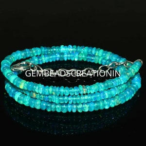 Puede incluir: Una hebra de cuentas de ópalo azul turquesa con un cierre plateado. Las cuentas son pequeñas y redondas, y tienen un ligero brillo iridiscente.