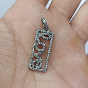 May include: A silver pendant with a rectangular frame and the word "LOVE" spelled out in black diamonds.