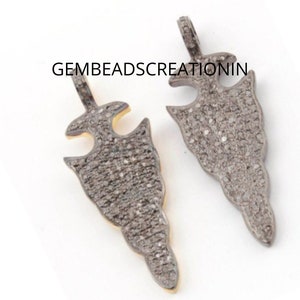 May include: Two silver arrowhead pendants with a pave setting of small diamonds. The pendants have a loop at the top for attaching to a chain or cord.