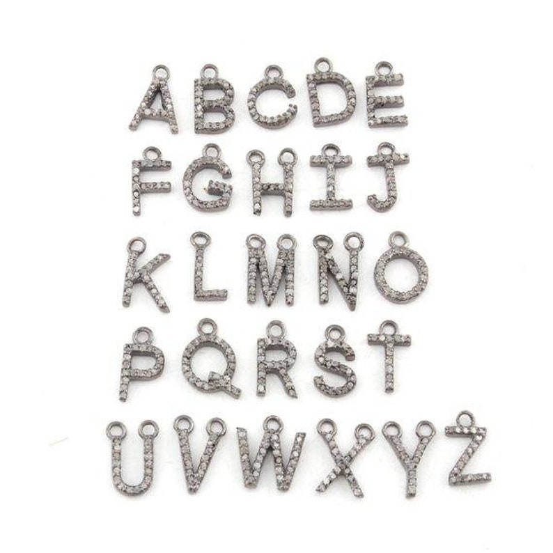 May include: A set of silver alphabet charms, each with a small loop for attachment. The letters A to Z are shown, each encrusted with small, sparkling embellishments. The charms are arranged on a white background.