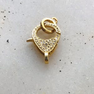 May include: Gold-tone clasp with clear crystal accents. The clasp is designed to be used for necklaces or bracelets.