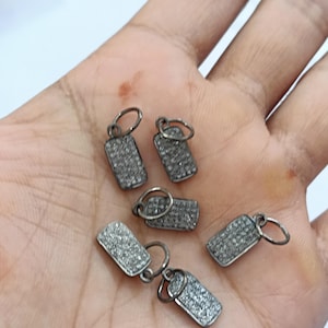 Könnte beinhalten: Sechs silberfarbene Anhänger in rechteckiger Form mit einem Diamanten-Pave-Design. Jeder Anhänger hat eine kleine Öse oben zum Anbringen an eine Halskette oder ein Armband.