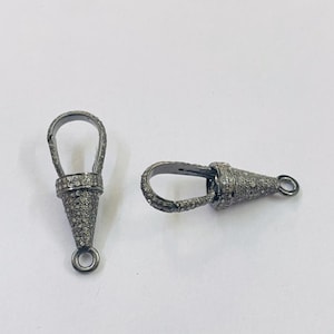 May include: Two silver-toned cone-shaped jewelry clasps with a diamond-like pattern. Each clasp has a loop at the top and a small ring at the bottom.
