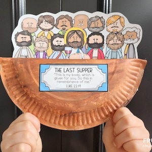 May include: A brown paper plate with a white border and a blue and white sign that reads "The Last Supper" with the Bible verse Luke 22:19. The sign is attached to the plate with a stapler. There are 12 cartoon figures of men around the edge of the plate. The figures are all wearing different colored clothing and have different facial expressions.