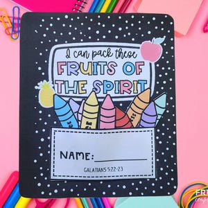 May include: Black notebook cover with white polka dots and the text "I can pack these FRUITS OF THE SPIRIT." Includes a space for the name and the Bible verse Galatians 5:22-23. Features colorful crayon and fruit illustrations.