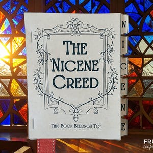 Puede incluir: Un libro titulado "The Nicene Creed" con un borde decorativo y el texto "This book belongs to:". El libro está abierto, revelando el título en letras grandes y en negrita. El fondo presenta una vidriera con colores vibrantes.