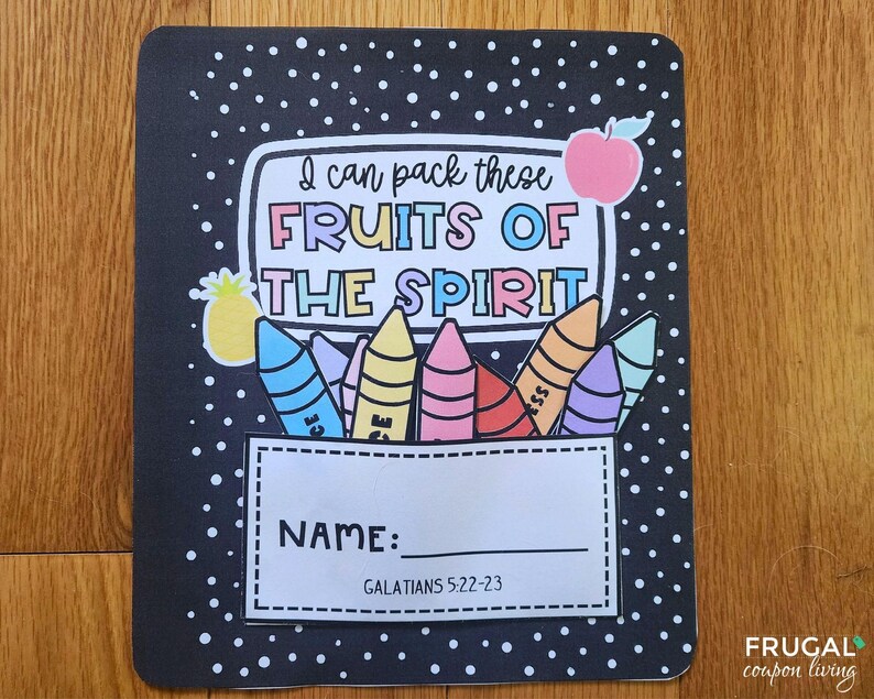 May include: A black notebook cover with white polka dots and colourful illustrations. The text "I can pack these FRUITS OF THE SPIRIT" is displayed above a crayon design. Below is a space for a name and the scripture reference Galatians 5:22-23.
