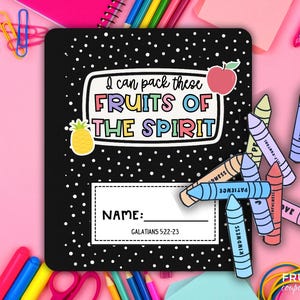 May include: Black notebook with white polka dots and the text "I can pack these FRUITS OF THE SPIRIT." Includes a pineapple and apple sticker. Crayon cutouts with words like "Kindness" and "Patience" are scattered around the notebook.