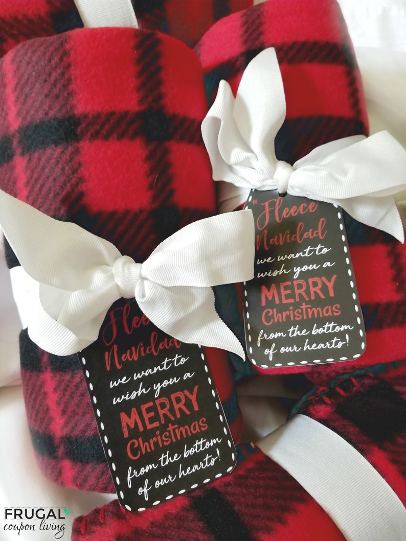 May include: Red and black plaid fleece blankets tied with white bows and gift tags. The tags read "Fleece Navidad, we want to wish you a Merry Christmas from the bottom of our hearts!" A festive holiday gift.