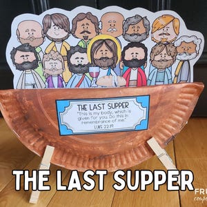 May include: A brown paper plate with a scene depicting the Last Supper. The plate is propped up on two wooden clothespins. The scene includes Jesus and his disciples, with the text "THE LAST SUPPER" and a quote from Luke 22:19.