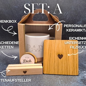 May include: A gift set labelled "SET: A" includes a ceramic mug, wooden coaster, card holder, and gift box. The mug has "DAD" printed on it. The wooden coaster and card holder feature heart cutouts. The set also includes labels.