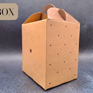 May include: A brown cardboard gift box with a handle and lid, adorned with small heart motifs. The word "BOX" is printed on the top left. Ideal for small gifts or packaging, it has a rustic aesthetic.