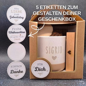 May include: A gift box containing a personalised mug, wooden accent, and decorative items. The mug is white with the name "SIGRID" and a heart. Includes round stickers with phrases like "Happy Birthday" and "Thank You".