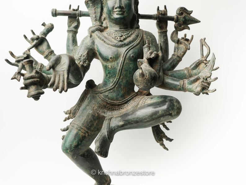 May include: A green bronze statue of a Hindu deity with multiple arms holding various objects. The deity is depicted in a dancing pose with one leg raised.