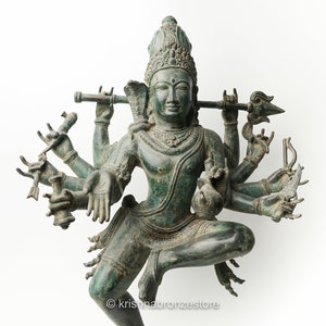 May include: A green bronze statue of a Hindu deity with multiple arms holding various objects. The deity is in a dancing pose with a crown on its head.