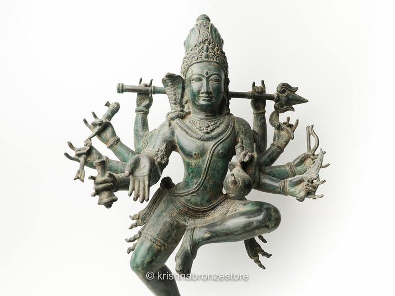 May include: A green bronze statue of a Hindu deity with multiple arms holding various objects. The deity is in a dancing pose with a crown on its head.