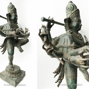 May include: A four-armed bronze statue of a Hindu deity, possibly Vishnu, playing a flute. The statue is in a dancing pose and has a green patina.