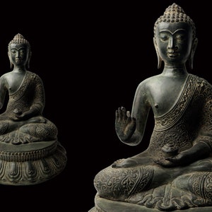May include: Two dark bronze statues of Buddha sitting in meditation pose. The statues are intricately detailed with ornate clothing and a serene expression.