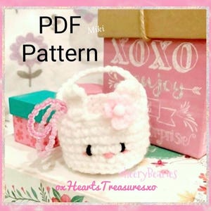 May include: PDF pattern for crocheting a white kitty cat purse with a pink flower. The purse has black eyes and a pink nose. The pattern is available for download.