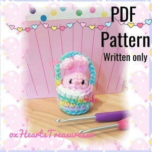 May include: A crochet pattern for a pink bunny in a pastel coloured basket. The pattern is written only and available as a PDF download. The image shows the finished amigurumi bunny and basket.