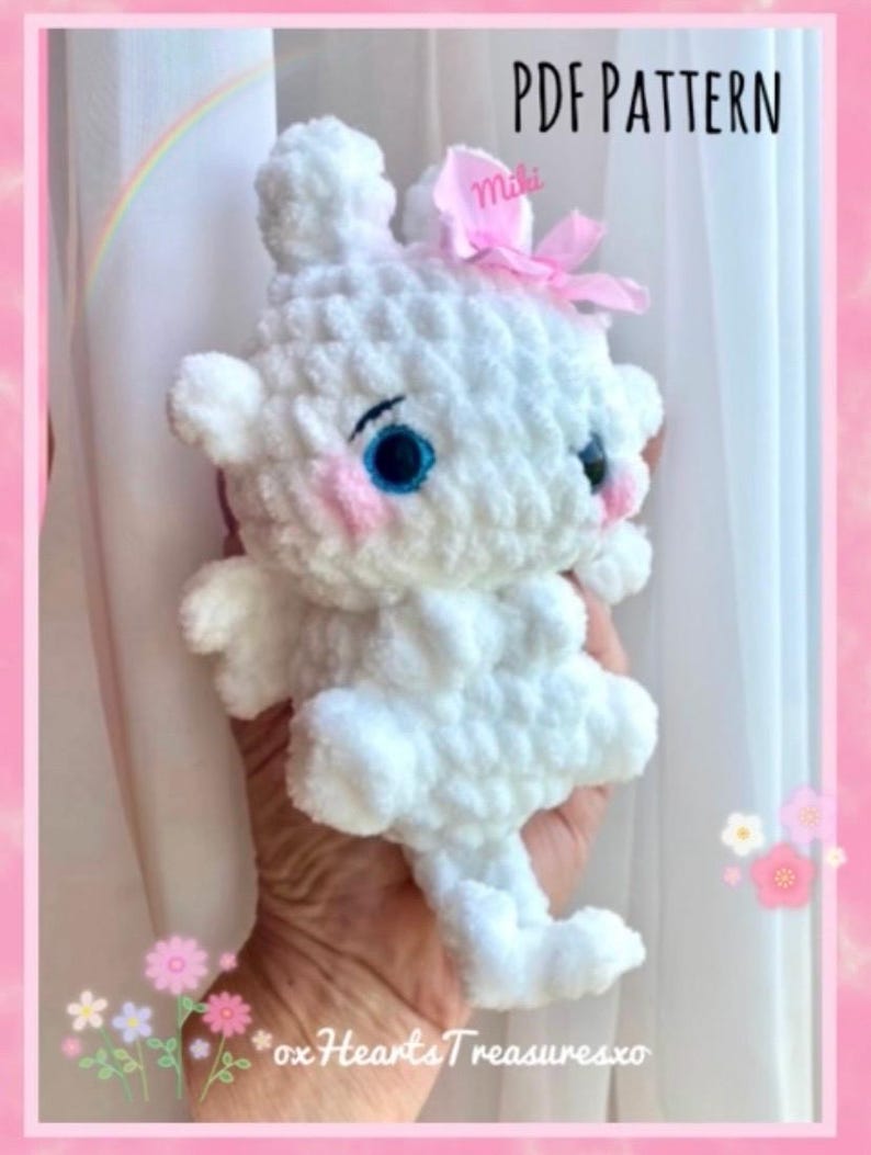 May include: White crocheted amigurumi plush toy with blue eyes and pink cheeks. The toy has a pink bow with the word "miki" on it. The toy is being held by a hand. The image has the text "PDF PATTERN" and "oxHeartsTreasuresxo".