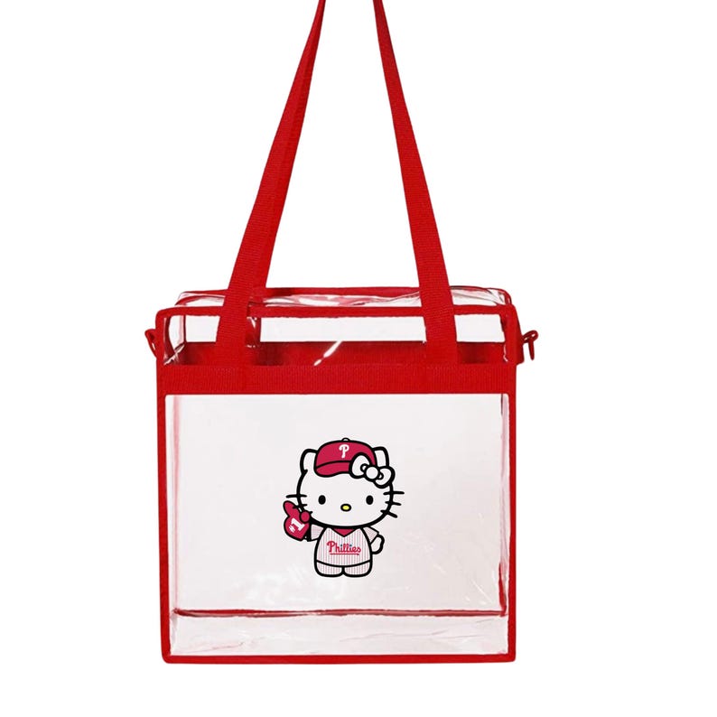 May include: Clear red and white tote bag with a Hello Kitty graphic wearing a Philadelphia Phillies baseball cap and holding a baseball glove. The text "Phillies" is on the shirt.