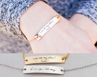 Puede incluir: Tres pulseras de barra de oro con diferentes grabados. La pulsera superior tiene el mensaje escrito a mano "With all my love! Mom". La pulsera del medio tiene el mensaje escrito a mano "Love you always". La pulsera inferior tiene una imagen dibujada a mano de una familia.