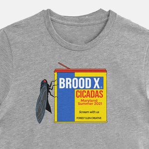May include: A heather gray t-shirt featuring a graphic of a cicada and a can labeled "Brood X Cicadas." The can design is yellow, blue, and red, with text that reads "Maryland Summer 2021" and "Scream with us."