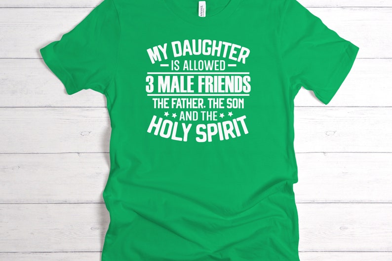 K&ouml;nnte beinhalten: Ein leuchtend gr&uuml;nes T-Shirt mit wei&szlig;em Text. Der Text lautet: "MY DAUGHTER IS ALLOWED 3 MALE FRIENDS THE FATHER. THE SON AND THE HOLY SPIRIT". Das Shirt wird vor einem wei&szlig;en Holzgrund gezeigt.