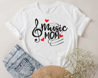 Pode incluir: Camiseta branca com uma clave de sol preta e o texto "music mom" em preto com corações vermelhos.