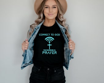 May include: Black t-shirt with the text "CONNECT TO GOD" above a WiFi symbol and cross graphic. Below the graphic, the text reads "THE PASSWORD IS: PRAYER" in a teal color. The shirt is worn by a person wearing a denim jacket and a hat.