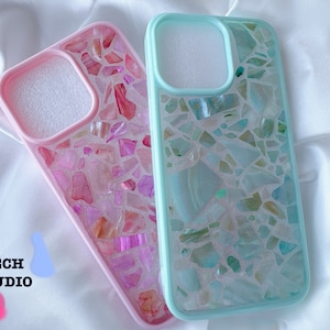 May include: Two iPhone cases with a mosaic design. One case is pink with pink and white mosaic pieces. The other case is light blue with blue and white mosaic pieces.