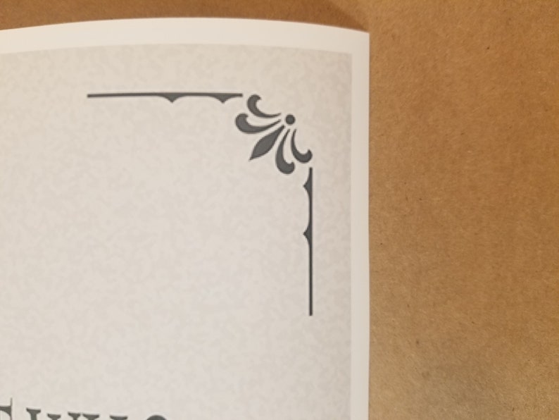 May include: A corner detail of a printed page featuring a decorative gray floral design. The design is composed of stylized leaves and a central dot, with a border of short vertical lines. The paper has a textured, off-white appearance.