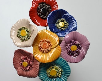 May include: A bouquet of seven ceramic poppy flowers in various colors, including red, blue, pink, yellow, and white. Each flower has a detailed center and a glossy finish.