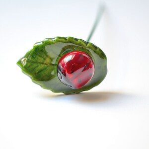 Hand-made ceramic ladybug on leaf for decorating ceramic flower bouquet.