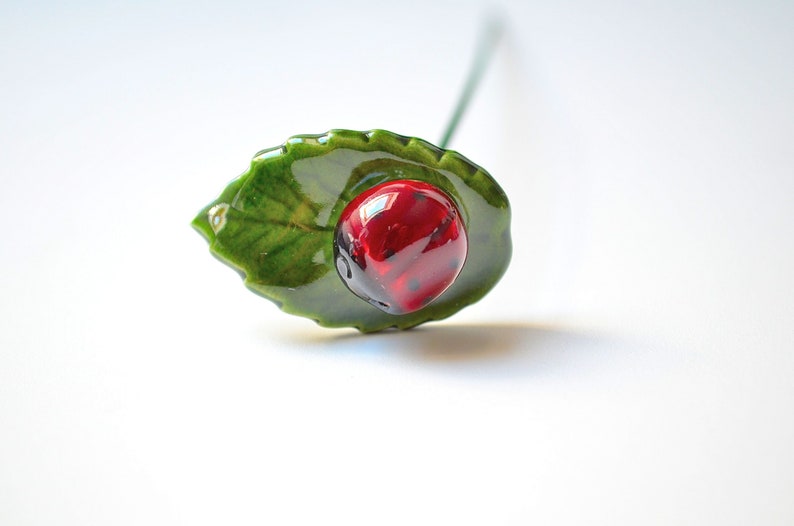 Hand-made ceramic ladybug on leaf for decorating ceramic flower bouquet.